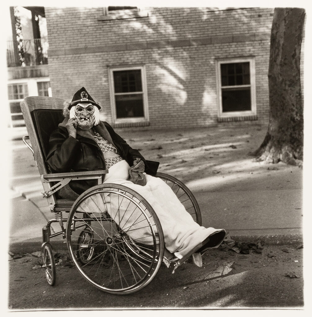 immagine per Masked woman in a wheelchair, Pa. 1970 © The Estate of Diane Arbus Collection Maja Hoffmann / LUMA Foundation