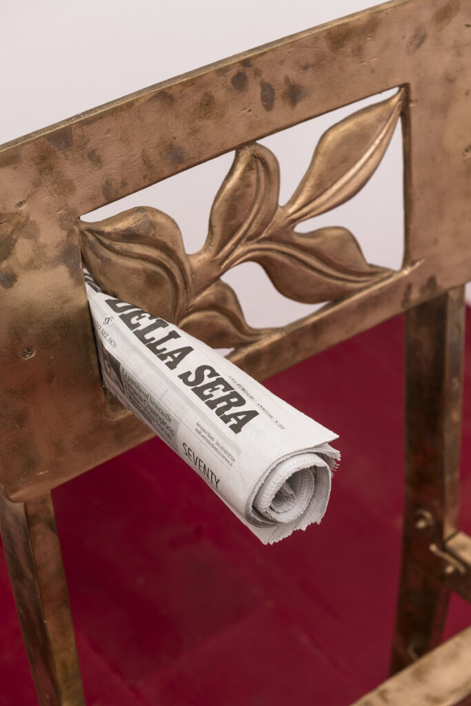 immagine per Sedia, 2023 Bronzo, giornale;cm 50x60x90 L’opera è la riproduzione in bronzo patinato nero in scala 1:1 della sedia che il pianista canadese di Toronto Glenn Gould (1932-1982) ha utilizzato per tutte le sue esibizioni, la sedia in questione è molto particolare, è bassa, fu realizzata dal padre di Gould ed apparentemente del tutto inadatta al suo scopo. La sedia originale è conservata presso The National Art Center di Ottawa. Nella spalliera della sedia, in alto è infilato un quotidiano arrotolato, il giornale va sostituito ogni giorno con quello del giorno in corso in modo che la scultura sia ogni giorno diversa da come era il giorno prima.