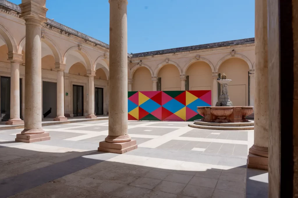 immagine per Karim Noureldin, Eight, 2024, Mixed Media, Site specific installation 250 x 800 x 100cm. Courtesy the Artist & Ortigia Contemporanea. Installation View Antico Mercato. Ph. Giacomo De Caro