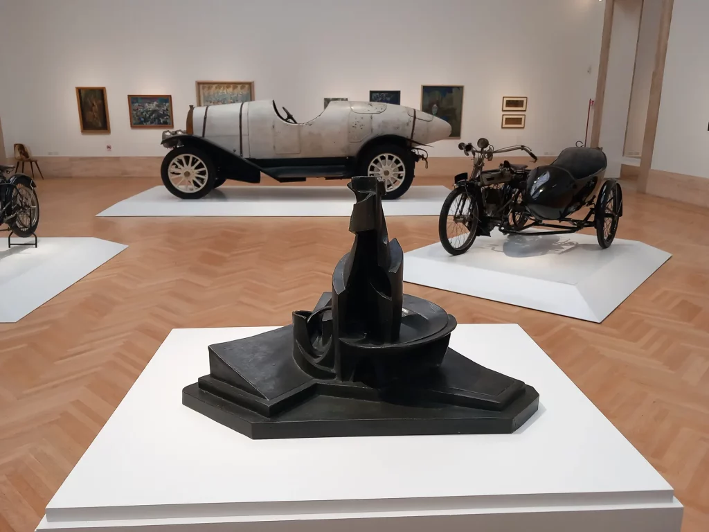 immagine per sala con auto e scultura U. Boccioni, Sviluppo di una bottiglia nello spazio, 1912 -dalla mostra Il Tempo del Futurismo -GNAM-C, Roma, 2024 -ph. Barbara Martusciello