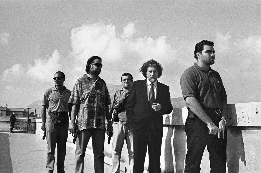 immagine per Letizia Battaglia Judge Roberto Scarpinato with his escort on the roof of the courthouse, Palermo, 1998. Courtesy of Archivio Letizia Battaglia.
