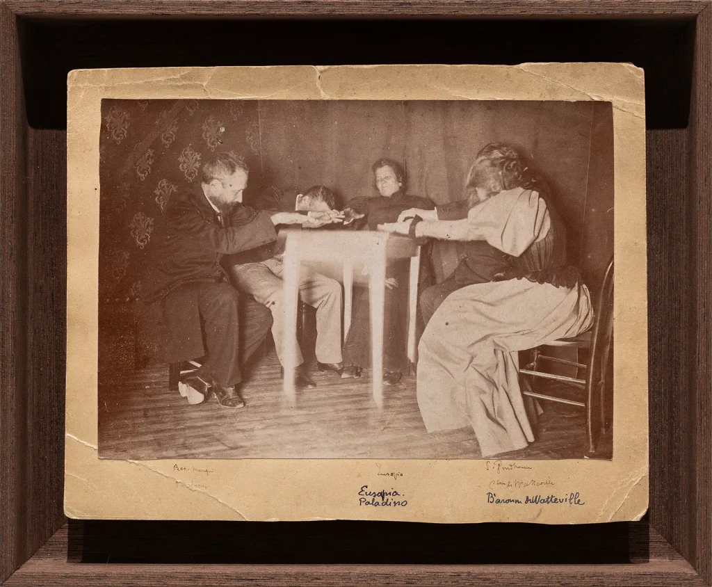 immagine per Eusapia Palladino Seduta con la medium Eusapia Palladino. Alla presenza di Sally Proudhomme e della Baronessa de Watteville, tra gli altri, 1985-1900 Annotazioni con inchiostro sotto l’immagine. Didascalia in matita nera sul verso del supporto. Stampa alla gelatina d’argento montata su cartone 11,9 x 17 cm; 14,8 x 19,3 cm foglio; 19,5 x 23,2 x 3,5 cm con cornice