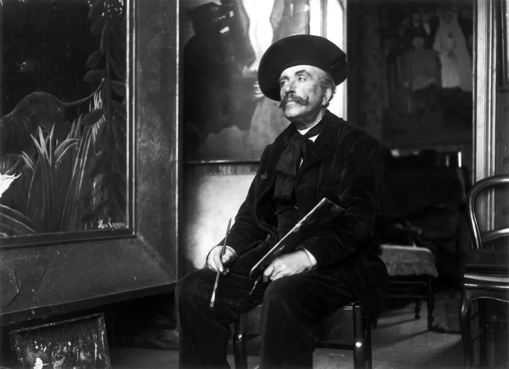 immagine di Henri Rousseau seduto accanto a Esploratori attaccati da una tigre, Cattiva sorpresa e Le nozze nel suo studio al 2 bis, rue Perrel a Parigi, 1907. Archivio fotografico Larousse, Parigi, Francia/ Bridgeman Images