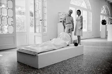 Fig. 14. Ugo Mulas, Leo Castelli e Beatrice Monti della Corte dietro a Giant Toothpaste Tube di Claes Oldenburg nelle sale dell’ex consolato americano alla XXXII Biennale di Venezia, giugno 1964 La fotografia è pubblicata in Flavio Fergonzi, Ugo Mulas/Jasper Johns. Fotografia come atto critico, 2026. © Eredi Ugo Mulas immagine per Fig. 14. Ugo Mulas, Leo Castelli e Beatrice Monti della Corte dietro a Giant Toothpaste Tube di Claes Oldenburg nelle sale dell’ex consolato americano alla XXXII Biennale di Venezia, giugno 1964 La fotografia è pubblicata in Flavio Fergonzi, Ugo Mulas/Jasper Johns. Fotografia come atto critico, 2026. © Eredi Ugo Mulas